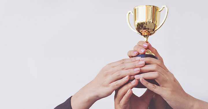 four hands holding small trophy